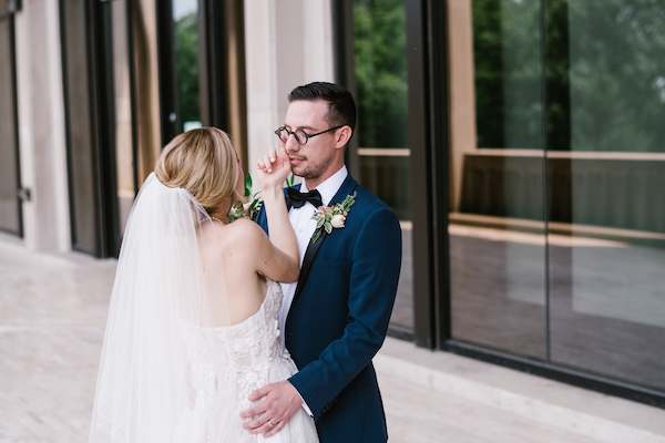 bride wiping tears from her groom's eyes after their first look at Newfields