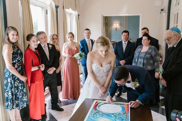 bride and groom signing their ketubah before their Newfields wedding ceremony