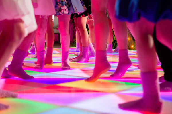 children in pink fuzzy socks dancing on an LED dancefloor at an Indianapolis Bat Mitzvah