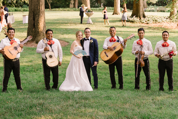 bride and groom posing for a photo with the mariachis at their wedding reception