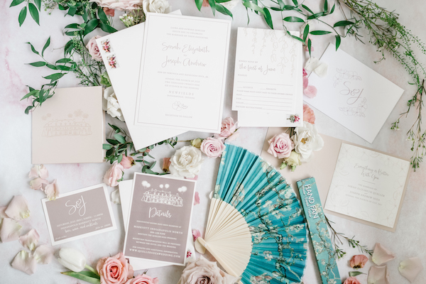flat lay photo of a custom wedding suite, program and fan showing the Lily House at new fields