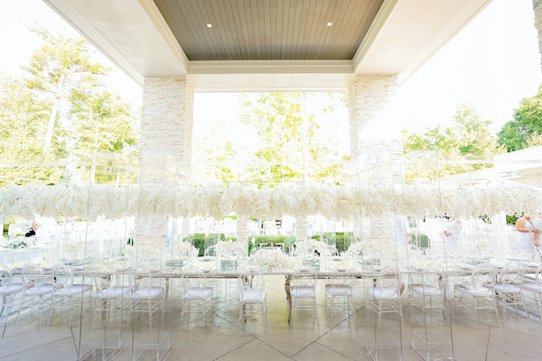 Luxurious mirrored feasting table under a canopy of white orchids at an Indianapolis white wedding