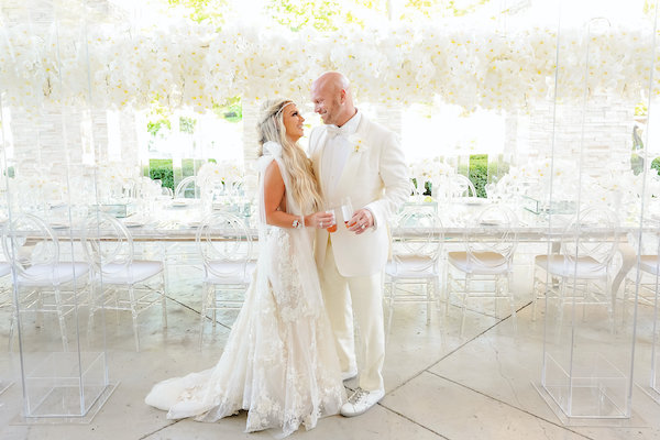 Bride and groom posing in front of their luxurious head table at their Indianapolis white wedding