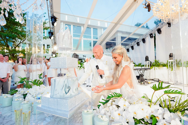 bride and groom cutting their four tiered white wedding cake at their luxurious Indianapolis white wedding