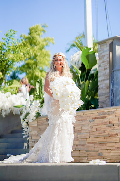 bride making her entrance carrying a large cascading white bridal bouquet 