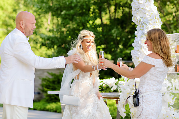 Mon Amie Events owner Monica Richard offering Champagne to newlywed bride and groom
