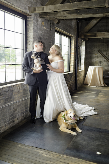 bride and groom taking photos with their dogs