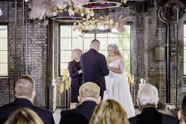 Ft Wayne bride and groom exchanging their vows during a wedding ceremony in an industrial wedding venue