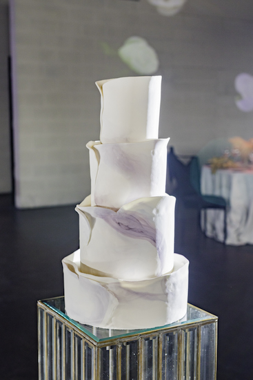 A unique contemporary four-tiered wedding cake with lavender marbling