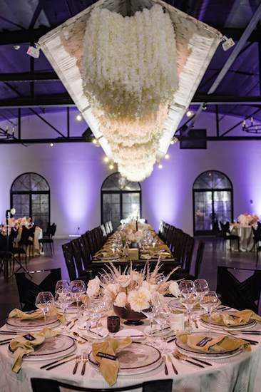 a long floral sculpture floating over a feating table