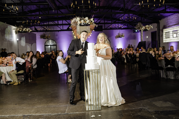 bride and groom standing next to their four tiered sculptural wedding cake