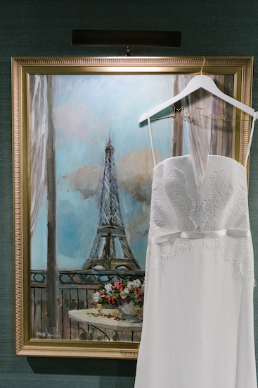 photograph of a bride's wedding gown in front of a painting of the Eiffel Tower at the Hotel Carmichael