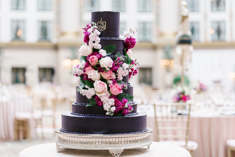 elegant seven tiered wedding cake with colorful flowers and the couple's custom carousel horse monogram