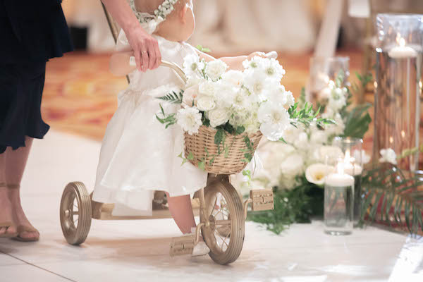Flowergirl riding a tricycle filled with flowers down the aisle