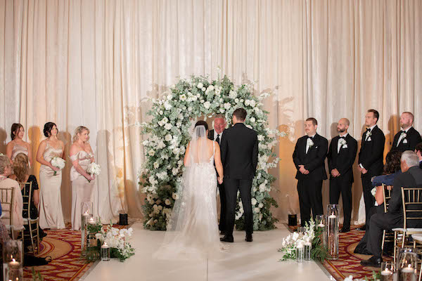 Bride and groom exchanging wedding voiws in from of a luxurious floral arch