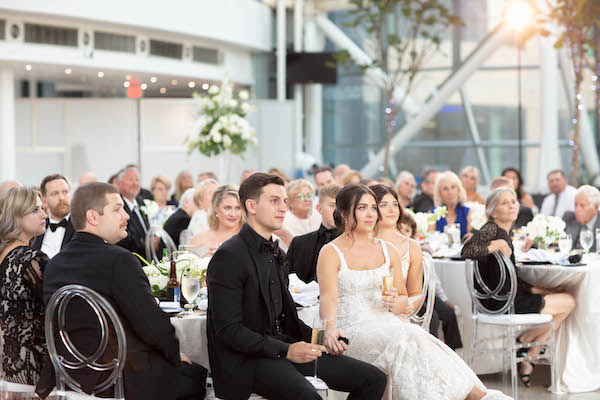 Bride and groom looking on as thier family and friends offer toasts