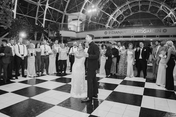 Bride and groom's first dance surrounded by family and friends with checkered flags