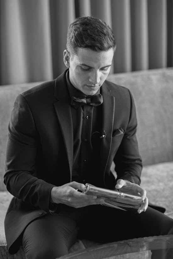 Indianapolis groom dressed in black holding a gift from his bride to be