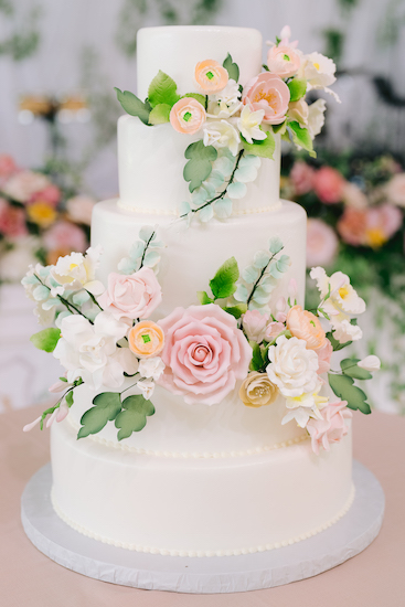 a three tiered white wedding cake with beautiful sugar flowers