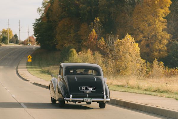 Bride and groom riding through the Indianapolis countryside in a vintage Rolls Royce