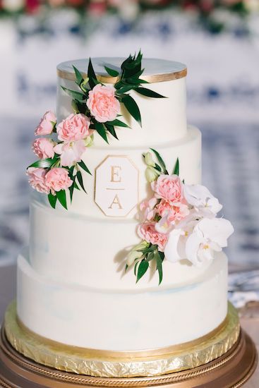 four-tiered white and gold wedding cake with pink flowers