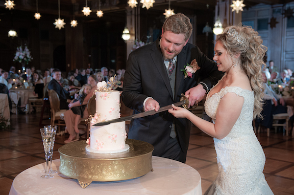 Bride and groom cutting their wedding cake with a family sword