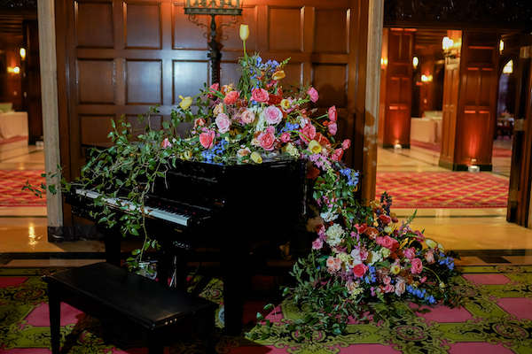 Baby grand piano covered with a blanket of bright flowers