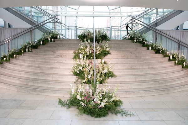 floral and candle lined stairs leading to a second event space