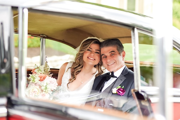 The bride and her father on their way to the wedding ceremony in a vintage car