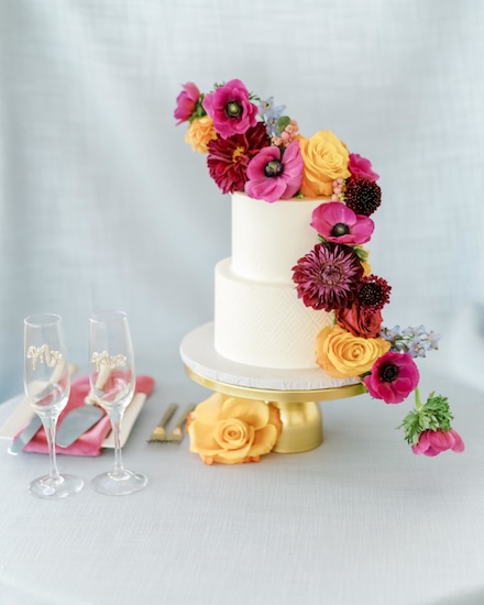 White wedding cake with brightly colored flowers