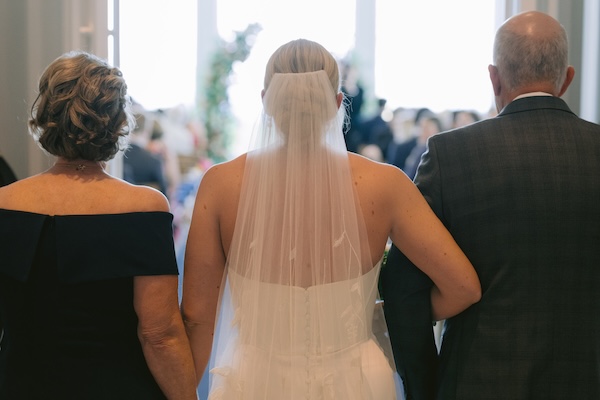 A bride and her parents walking down the aisle of the Straits Chapel at her wisconsin destination wedding.