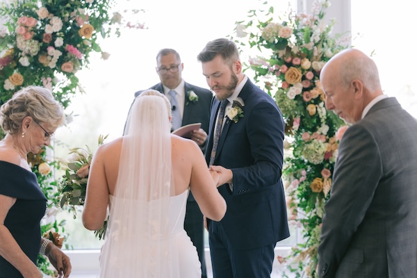 A bride and her parents reaching the groom during their Wisconsin destination wedding ceremony.