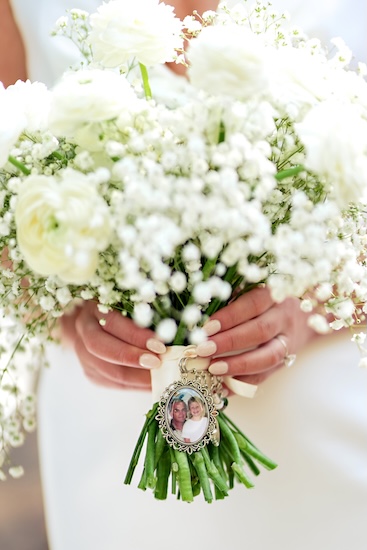 A white briudal bouquet witha family locket