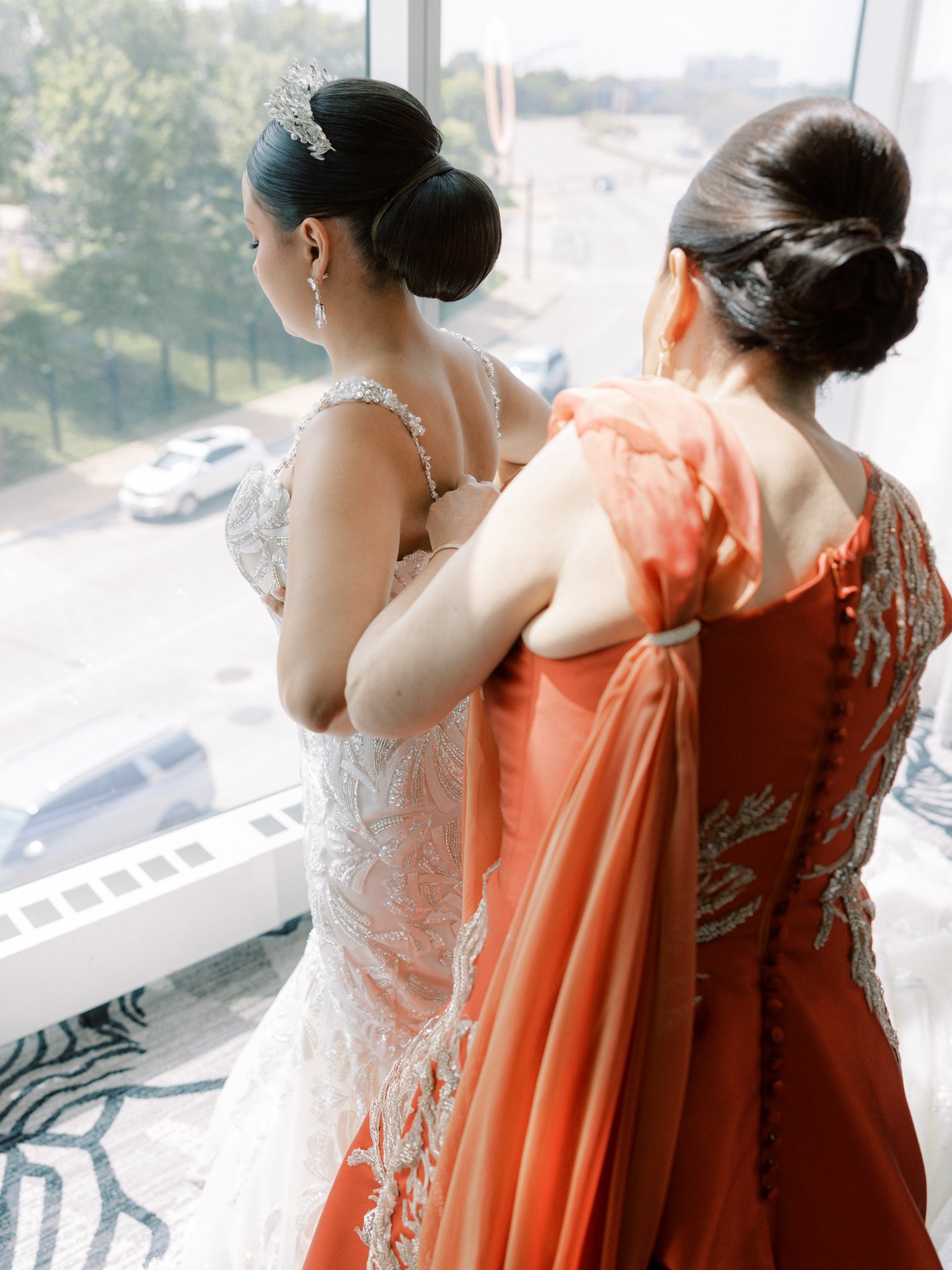 mother helping bride into her wedding dress