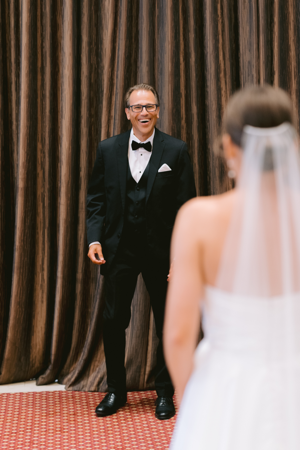 The bride’s father stands ready to embrace his daughter during their emotional first look.