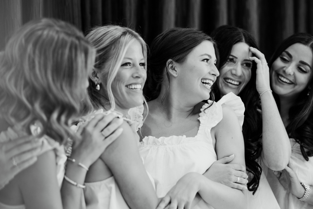 A candid black-and-white close-up of the bride laughing with her bridesmaids.