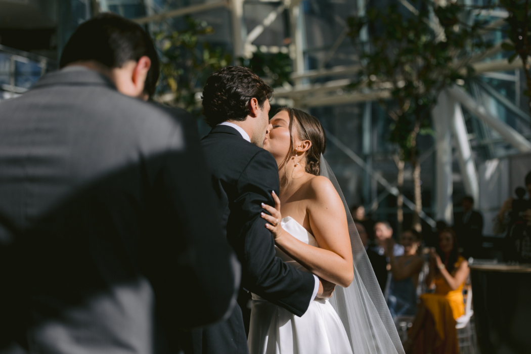 Bride and groom share their first kiss at the altar, framed by lush floral arrangements.