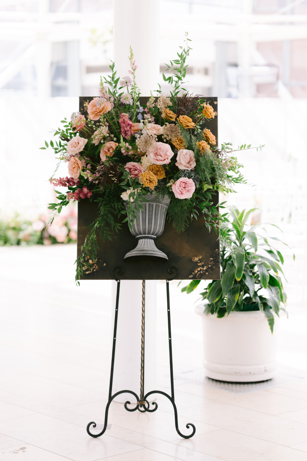 Dutch masters paintings inspired floral arrangement displayed on an easel, featuring pink, peach, and green blooms.