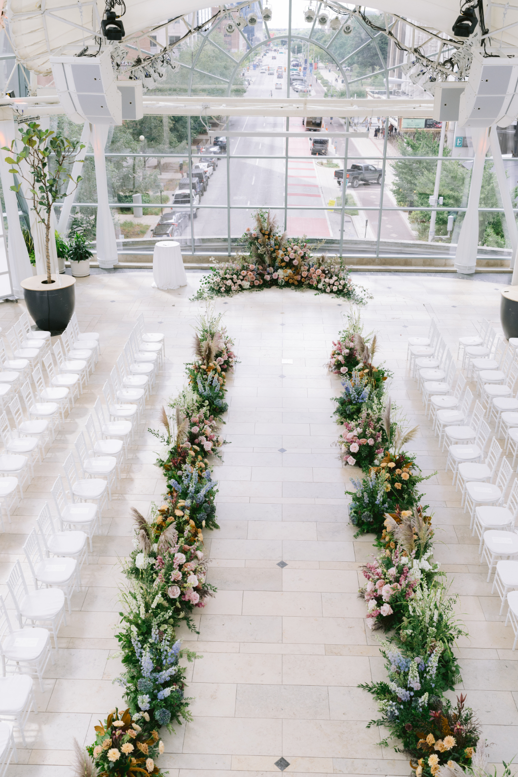 Wedding venue set up before the ceremony, with chairs lined along a floral-decorated aisle.